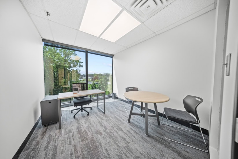 Bright, clean office with large window and minimal furniture.