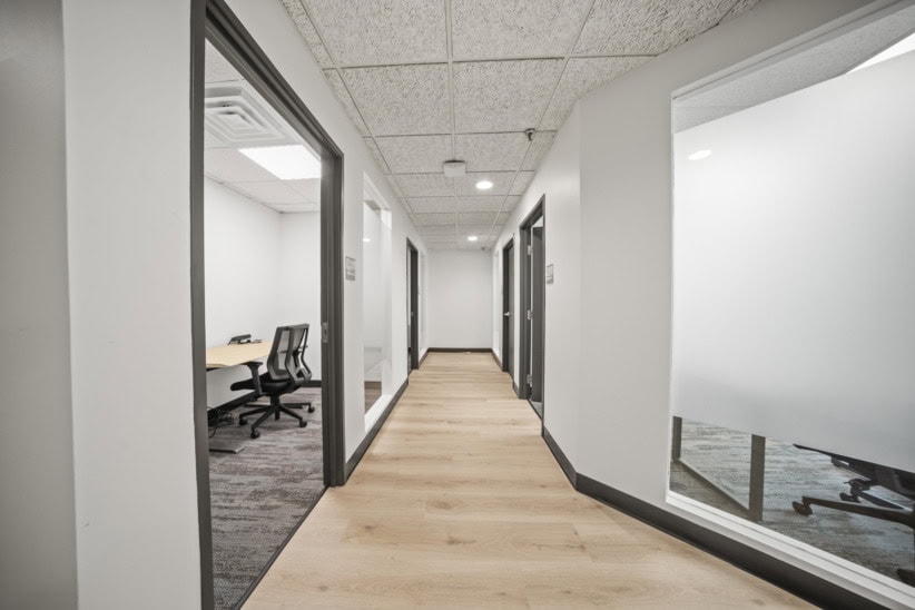 Contemporary office corridor with private rooms and glass walls.