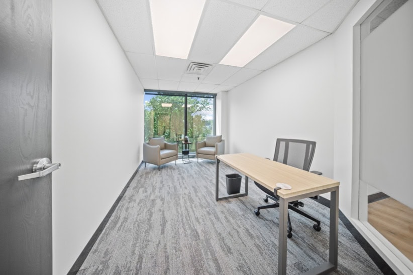 Bright, minimal office with a desk, chairs, and large window view.