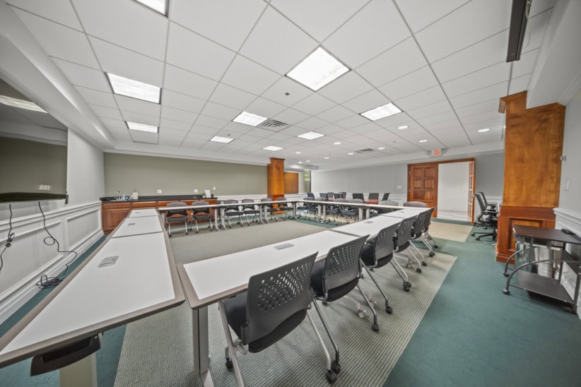 Modern conference room with U-shaped table and black chairs for meetings.