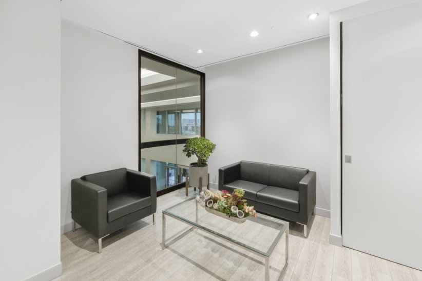 Contemporary office lounge in Oakville with black sofas and large window.