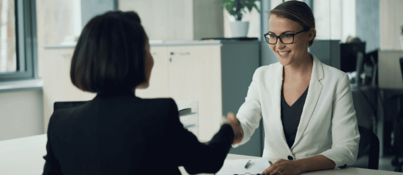 Businesswoman shaking hands in a coworking office space.