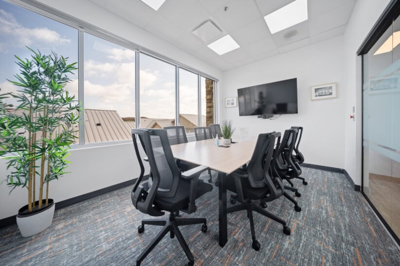 Modern conference room with large windows and a flat-screen TV.
