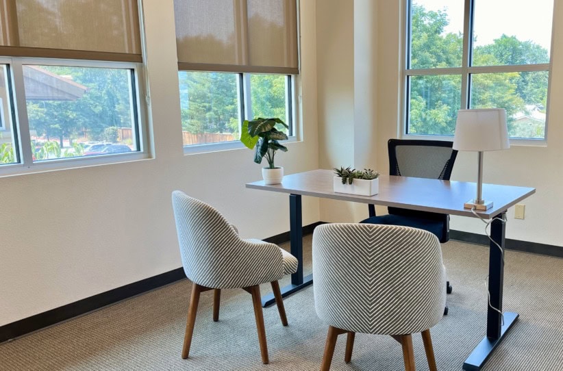 Modern office meeting room with large windows and minimal decor.