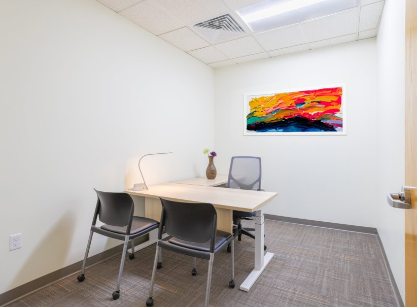 Modern office meeting room with a table, chairs, and colorful artwork on the wall.