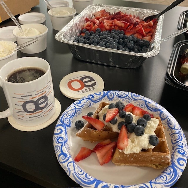 Waffle breakfast with fresh strawberries and blueberries at networking event.
