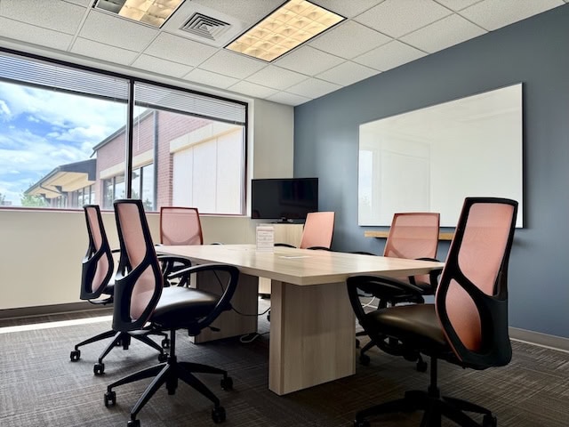 Modern office conference room with large window and ergonomic chairs.